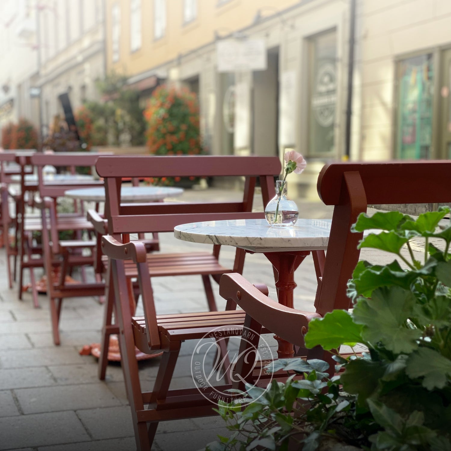 Röd karmstol med marmorbord utanför Café Vetekatten – klassiska utemöbler i elegant miljö, perfekt för stadscaféer och mysiga uteserveringar.