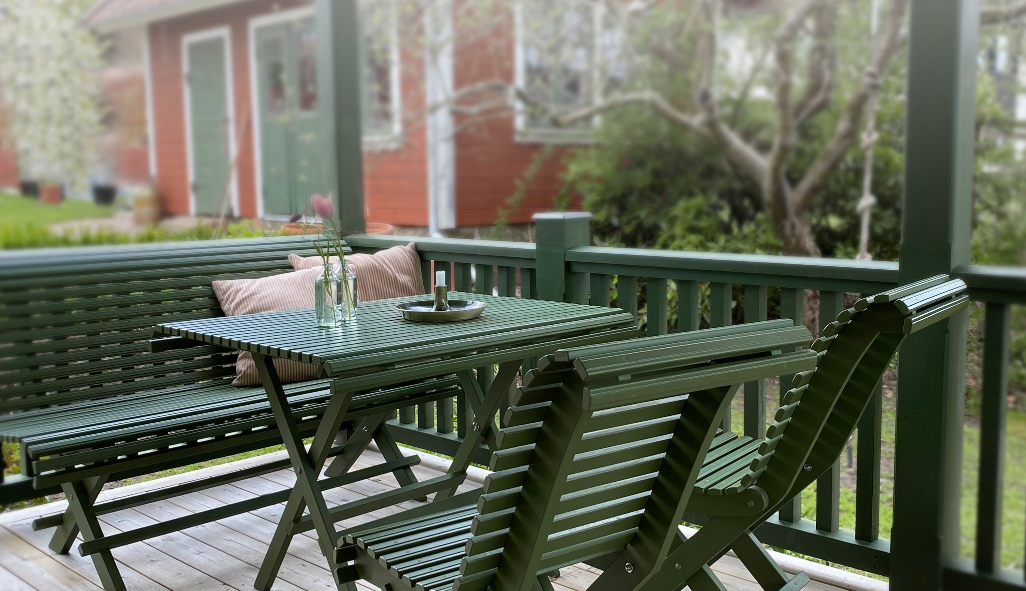 Gröna hopfällbara trädgårdsmöbler i trä – klassiskt matbord med stolar på en altan, perfekt för uteplatsen i en sekelskiftes- eller jugend miljö.