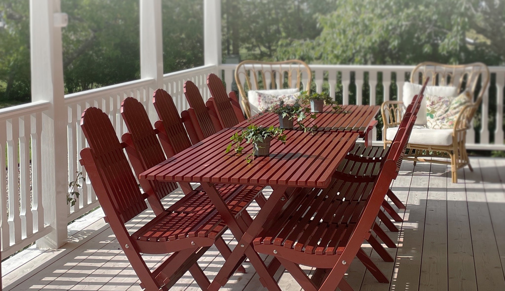 Röda hopfällbara trädgårdsmöbler i trä – långt matbord med stolar på en altan, perfekt för uteplatsen i klassisk miljö