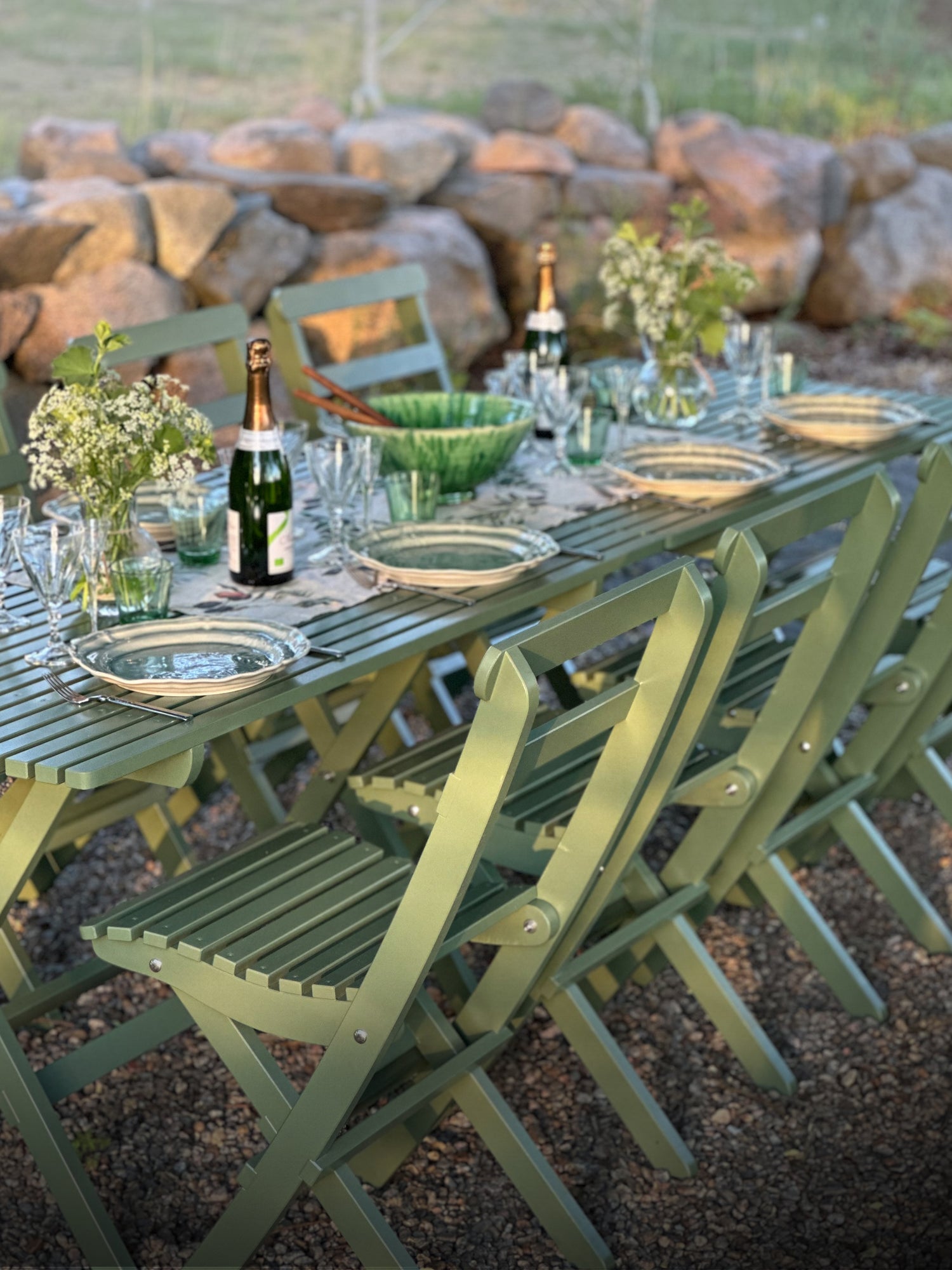 grönt sekelskiftesinspirerat matbord med stolar, dukat för middag i trädgården. Gammaldags utemöbler med tidlös design.